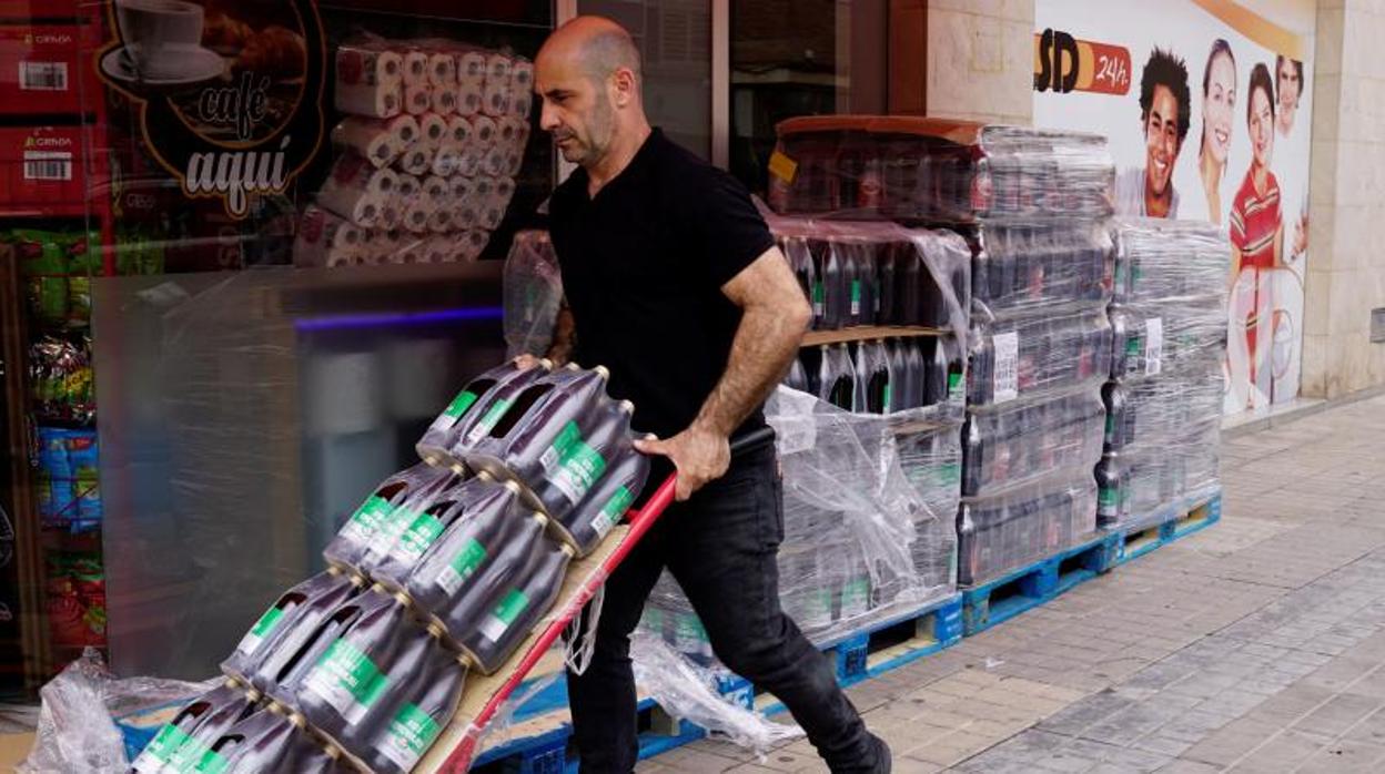 Un trabajador repone las botellas de cerveza en una tienda de alimentación durante el estado de alarma