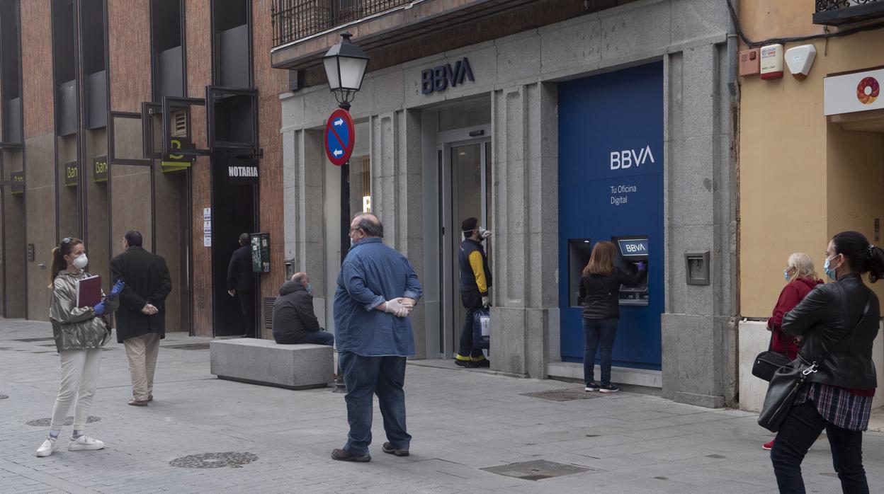 Varias personas haciendo cola ante una sucursal bancaria en Alcalá de Henares (Madrid)