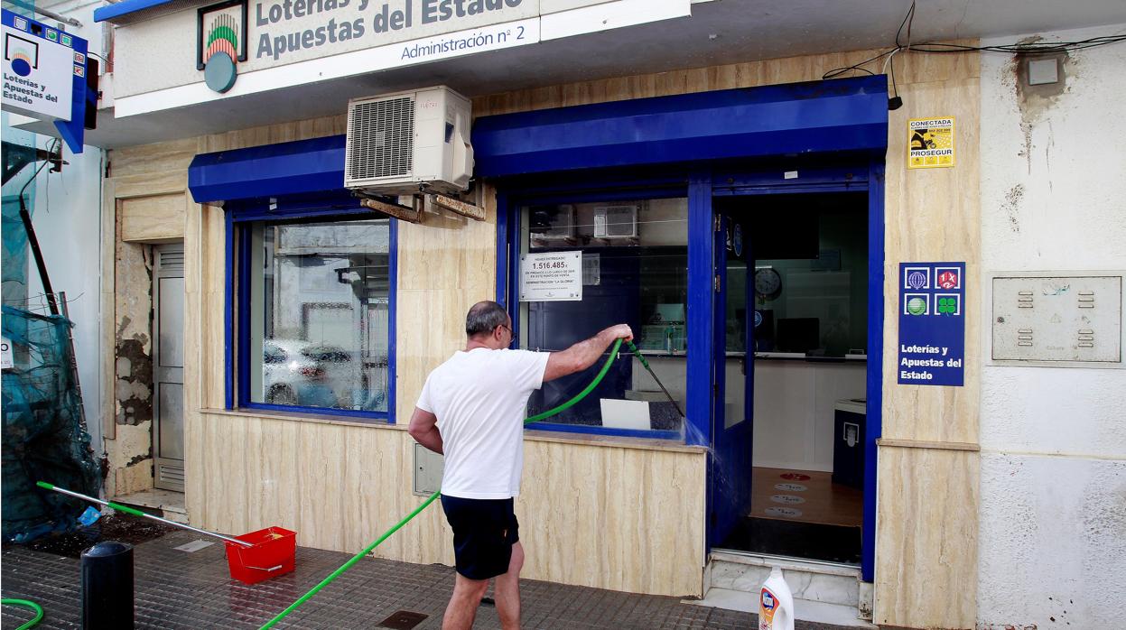 El dueño de un establecimiento de loterías, limpia y prepara su negocio