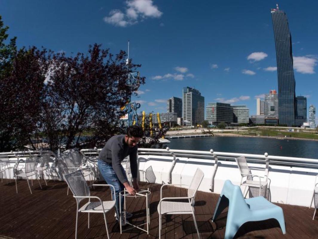 Un trabajador coloca las mesas y las sillas de acuerdo con las nuevas normas de seguridad por el coronavirus en un restaurante de la isla del Danubio, Viena