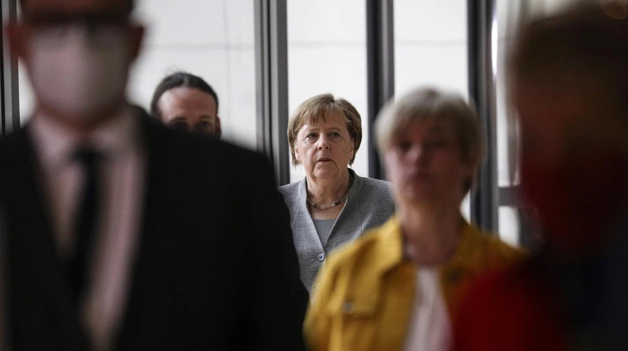 La canciller alemana, Angela Merkel (C) espera en la fila para emitir su voto