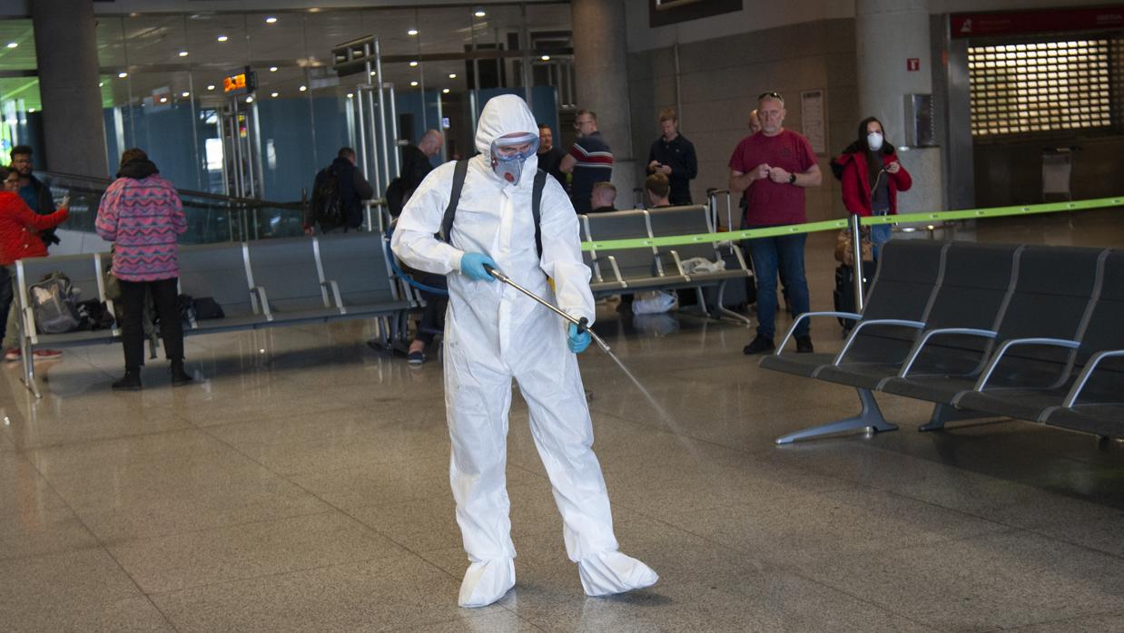 Un trabajador de la UME realiza labores de desinfección en el aeropuertto de Málaga, uno de los principales nudos de turismo internacional de Andalucía