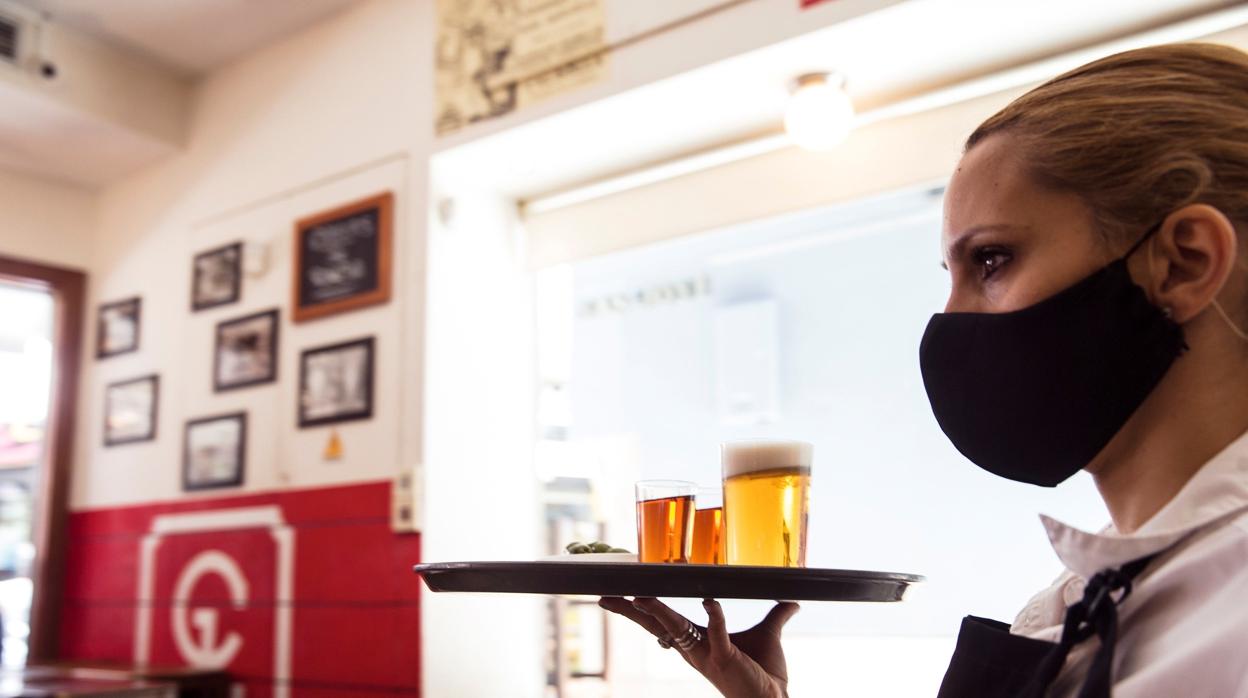 Una camarera porta una bandeja en un bar del centro de Málaga