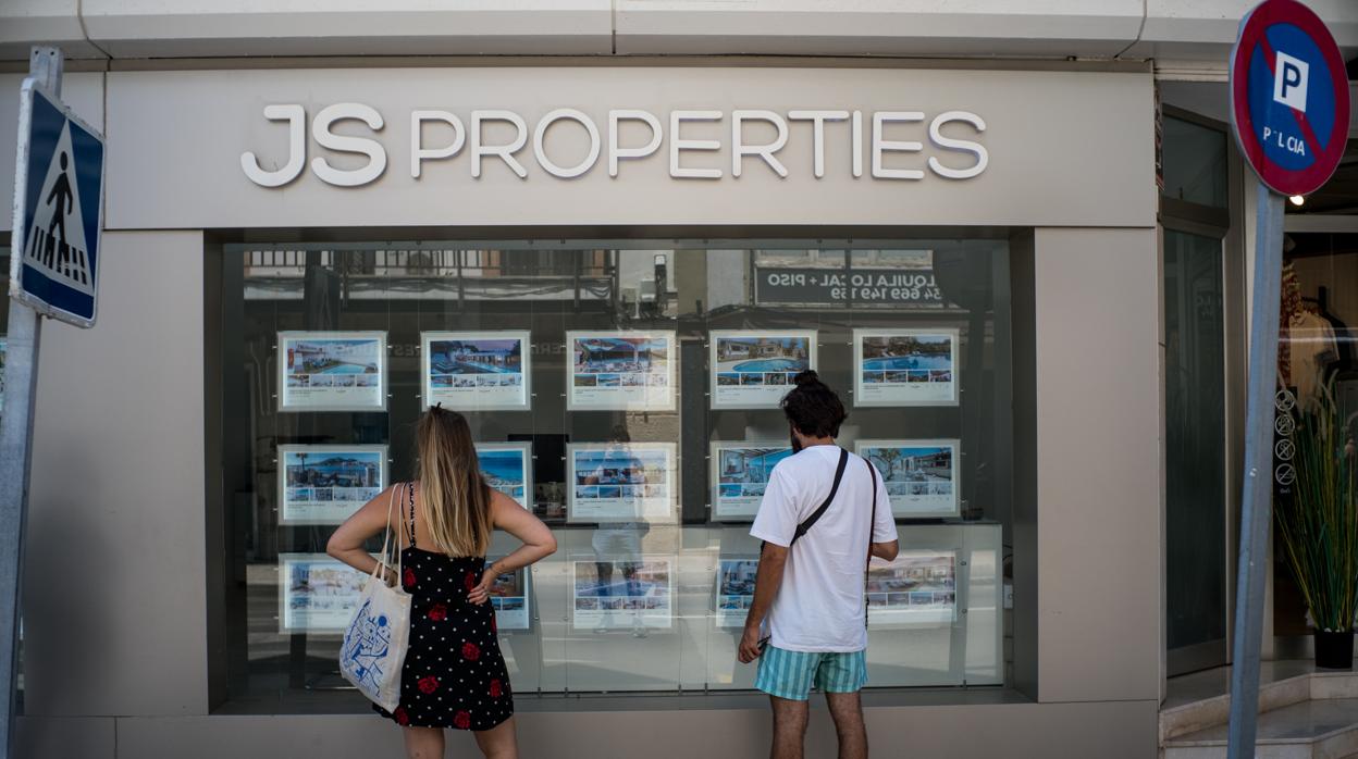 Dos personas observan inmuebles en alquiler y en venta en un escaparate de una inmobiliaria ubicada en Palma de Mallorca, durante el primer fin de semana después de que se levantara el estado de alarma por la crisis sanitaria del Covid-19. En Mallorca, Islas Baleares.