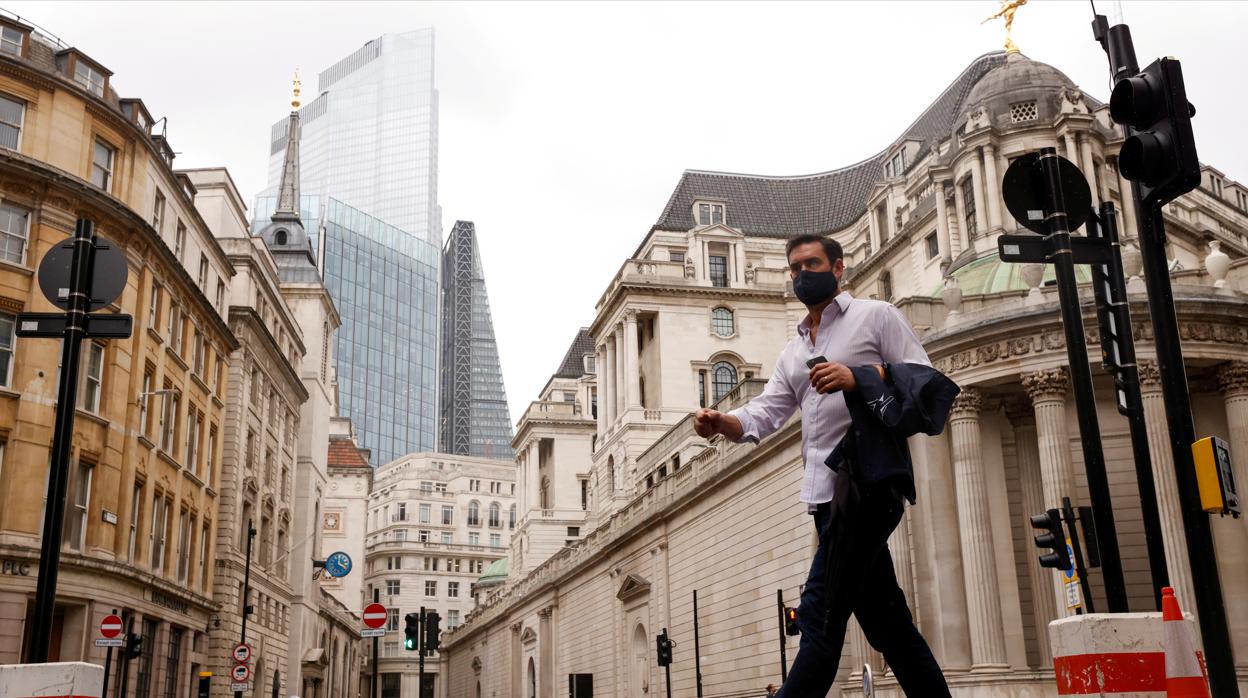 Un hombre caminando con mascarilla en la City de Londres