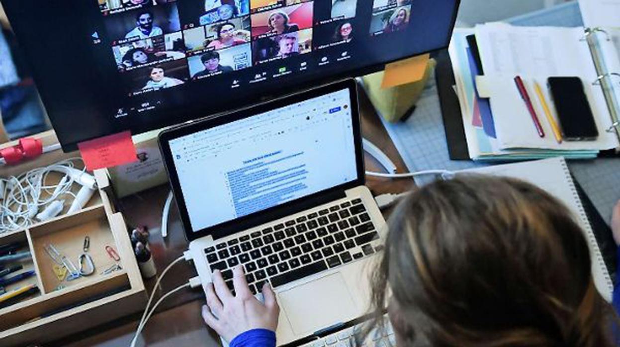 Una mujer teletrabajando desde casa con un portátil y haciendo una videoconferencia