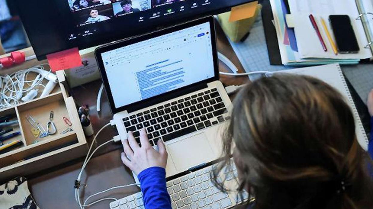 Una mujer teletrabajando desde casa con un portátil y haciendo una videoconferencia