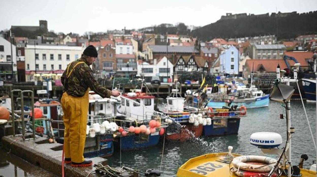 Un pescador limpia su barco en el puerto inglés de Scarborough