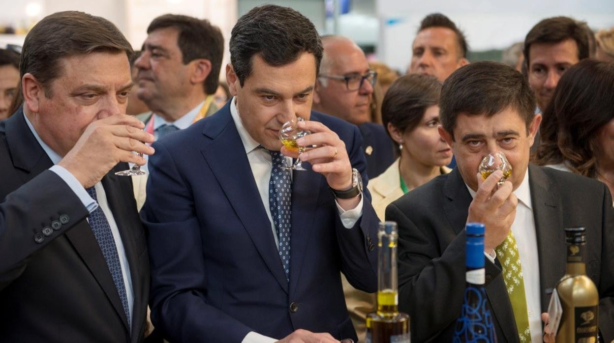 Foto de archivo de Juanma Moreno, en el centro, con el ministro de Agricultura, Luis Planas, y el presidente de la Diputación de Jaén, Francisco Reyes, en una cata de aceite