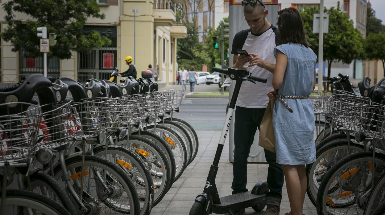 Una pareja alquilando a través de una aplicación un patinete eléctrico