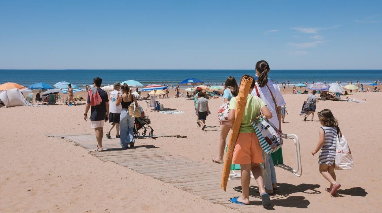 Bañistas se disponen a poner la sombrilla en la playa onubense de Punta Umbría