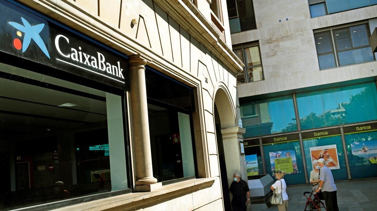 Una imagen de archivo de una oficina de Caixabank frente a otra de Bankia