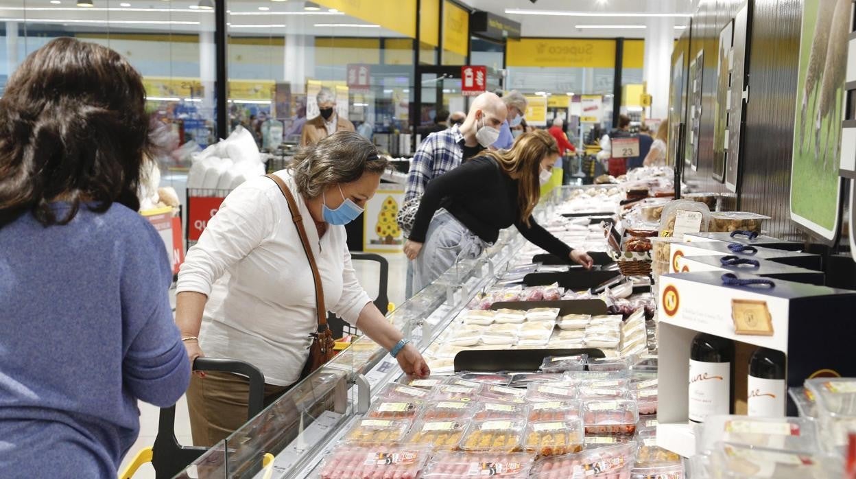 En la imagen, un grupo de personas compra en un supermercado