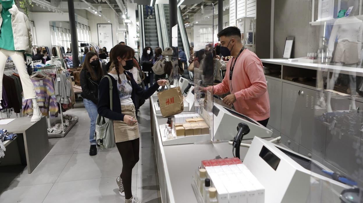 Un dependiente atiende a una clienta en un establecimiento comercial