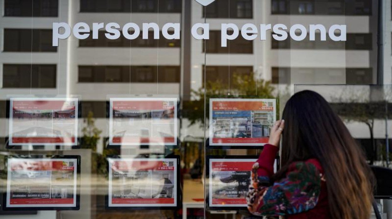 Una mujer mirando el escaparate de una inmobiliaria