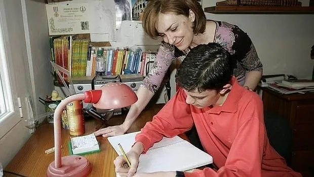 Un estudiante hace los deberes escolares junto a su madre