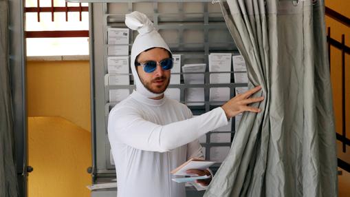 Un joven disfrazado de espermatozoide recoge las papeletas electorales