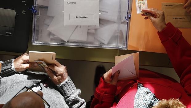 Dos españoles, ejerciendo su derecho al voto en un colegio electoral