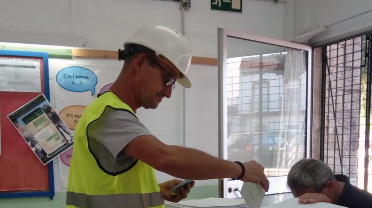 Uno de los padres de alumno votando con casco y chaleco amarillo