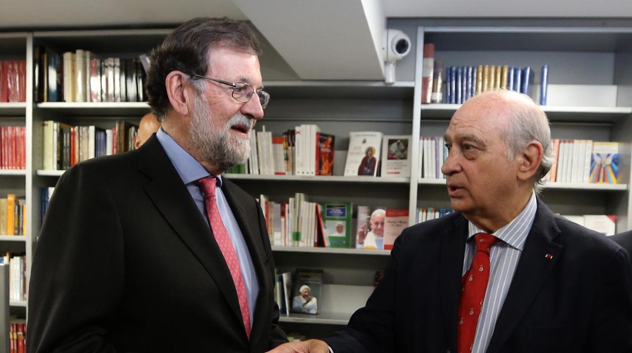 El expresidente del Gobierno Mariano Rajoy (i) conversa con el exministro del Interior Jorge Fernández Díaz (d) durante la presentación de su libro "Cada día tiene su afán", este jueves en la librería Neblí de Madrid