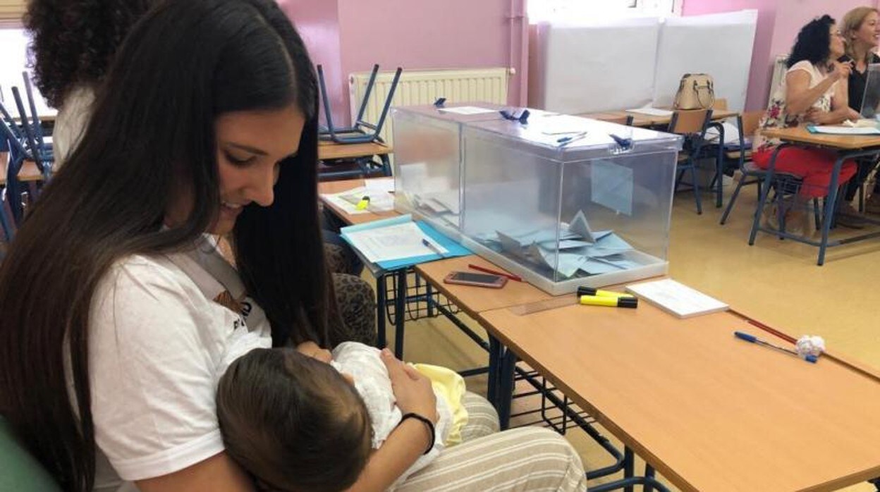 Una vecina de Arahal en Sevilla con su bebé, en la mesa electoral