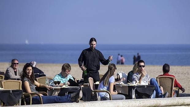 Imagen de un grupo de turistas en una terraza de la playa de la Malvarrosa de Valencia