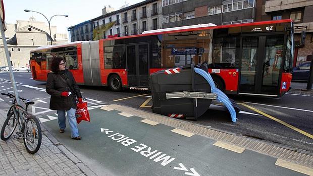 Un autobús urbano esquiva un contenedor tumbado y arrastrado por el viento en Zaragoza