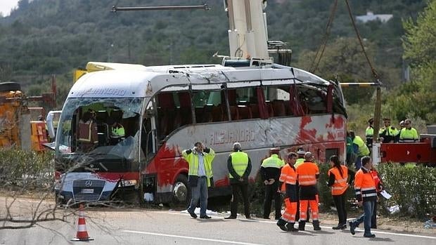 Diversos operarios tras levantar el autocar accidentado este fin de semana