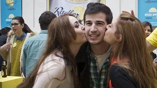 Dos chicas besan a un joven durante el evento de citas rápidas en Cibeles