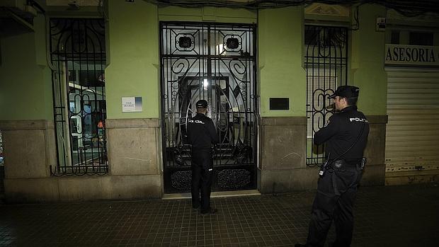 Dos agentes vigilan el edificio donde se hallaron los cuerpos