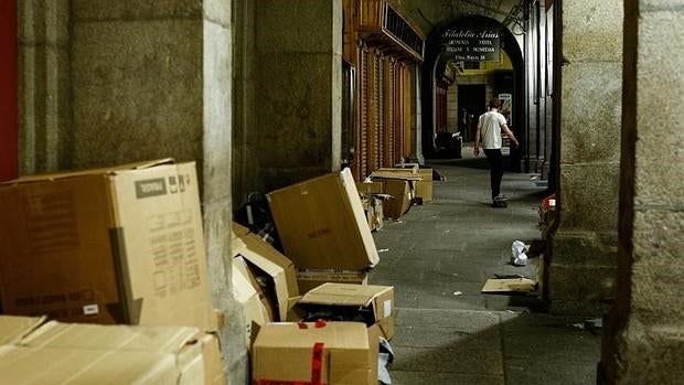 Varias personas sin techo se resguardan entre cartones en los soportales de la Plaza Mayor de Madrid