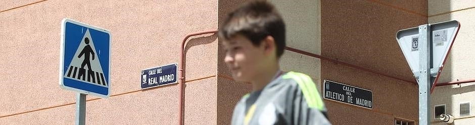 Un niño, con la camiseta del Real Madrid, cruza entre las dos calles de Carabanchel