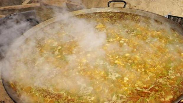 Una auténtica paella valenciana cocinándose al fuego de leña