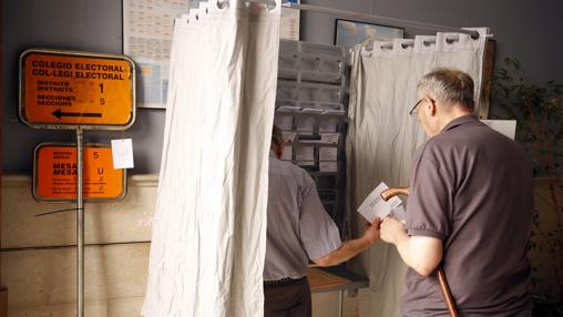 Dos personas preparan su voto en un colegio electoral