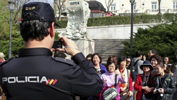 Un agente de la Policía Nacional hace una fotografía a unos turistas chinos