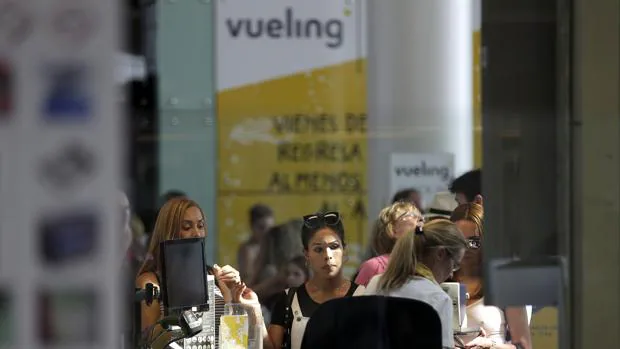 Personal de facturación de Vueling atiende a los viajeros en el Aeropuerto de El Prat tras las cancelaciones