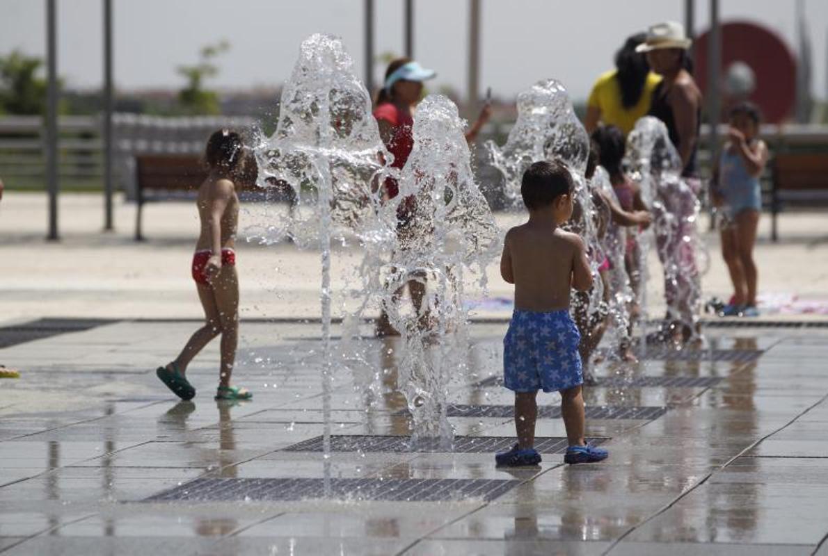 Un grupo de niños se refresca en una fuente