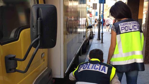 Dos agentes inspeccionan uno de los camiones a los que se robó la batería.