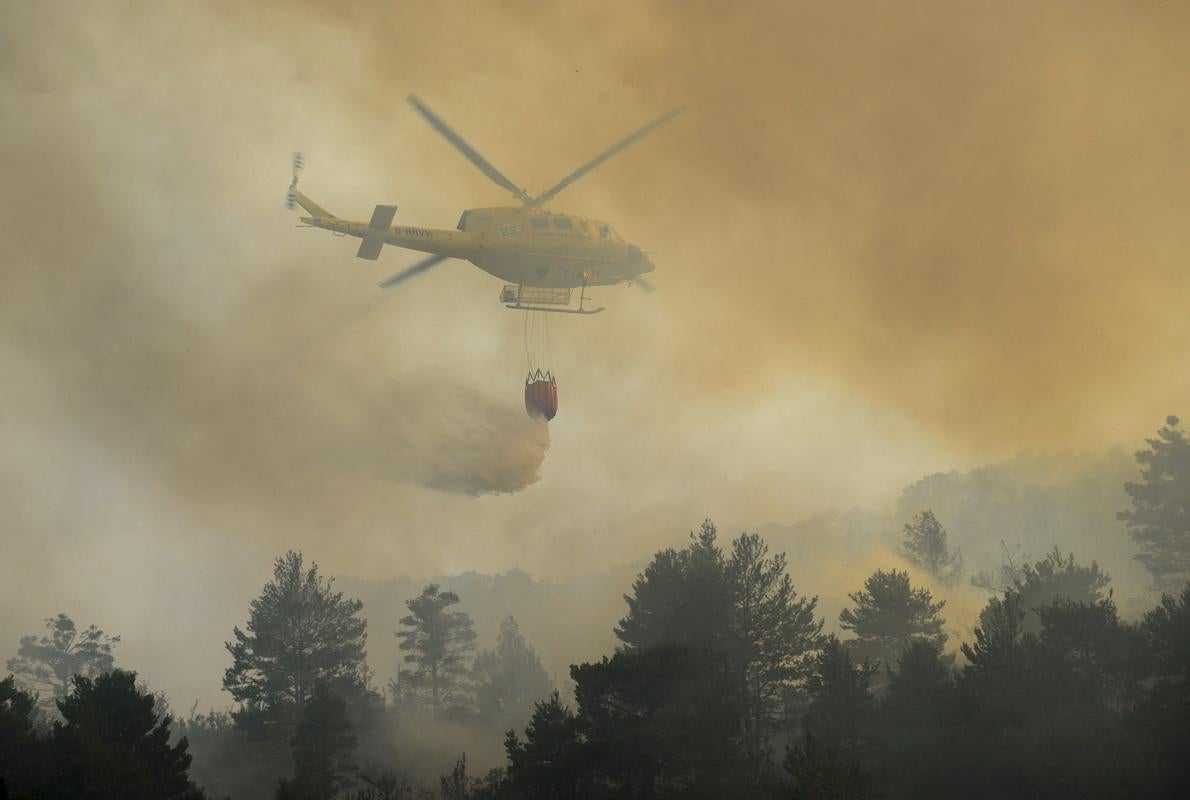 Un helicóptero lucha contra el fuego en la zona afectada por el incendio forestal