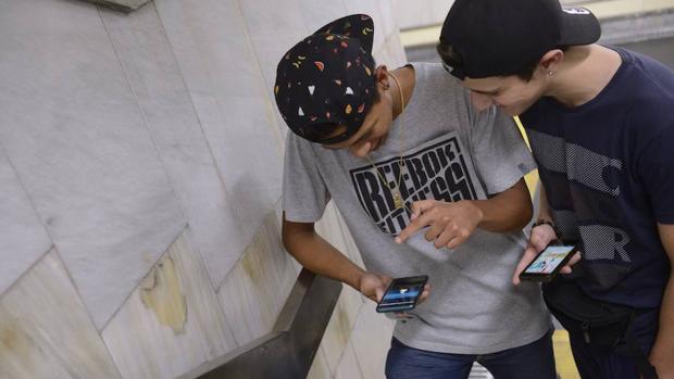 Dos jóvenes en el metro, en dirección a la quedada internacional de Pokémon GO en el Retiro