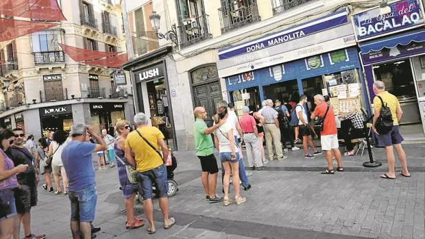 Cola de clientes esperando a comprar décimos de lotería en Doña Manolita