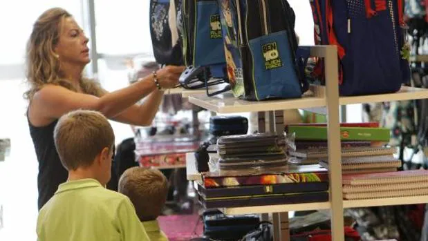 Una madre elige la mochila para sus hijos en un centro comercial