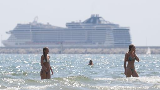 Dos turistas se bañan este jueves en Valencia frente a un crucero fondeado