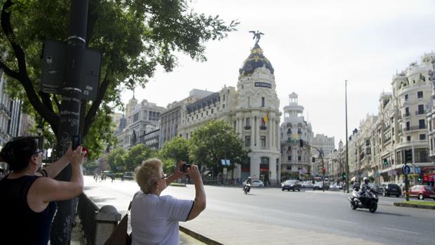 Dos turistas fotografían el Edificio Metrópolis, durante este verano