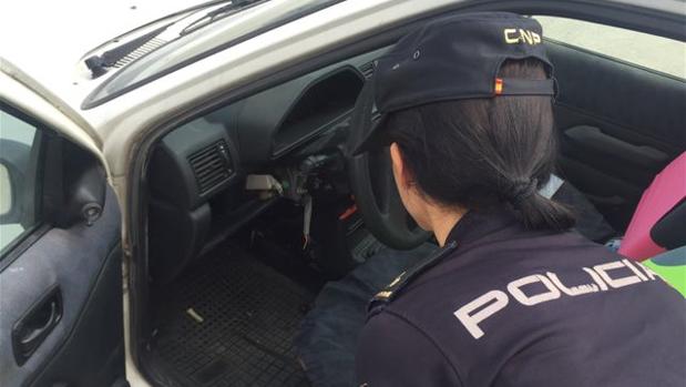 Una agente inspecciona el coche robado con el que el ladrón embistió a la moto de la Policía