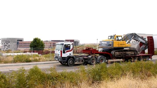 Un camión transporta una excavadora, en las inmediaciones del hospital