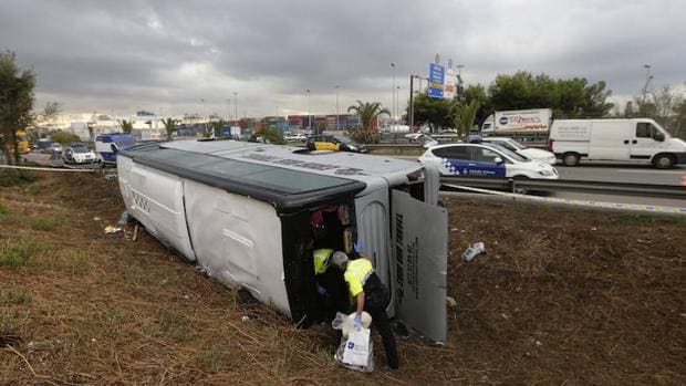 Unos operarios inspeccionan un autobús siniestrado en Barcelona