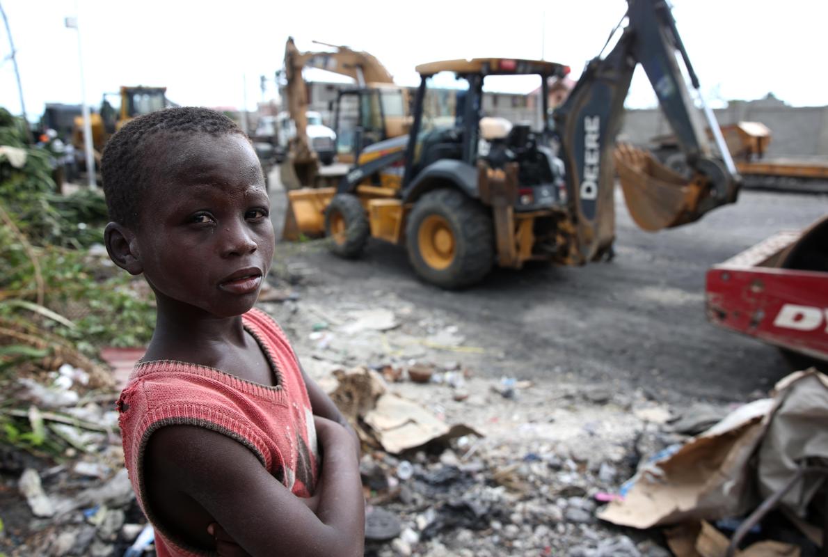 Un niño haitiano, ante las máquinas que trabajan en la reconstrucción de las zonas devastadas por el huracán