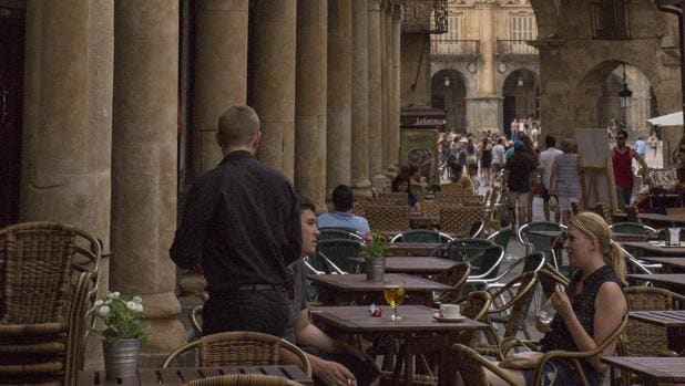 Un camareo atiende a dos turistas en una terraza de Salamanca