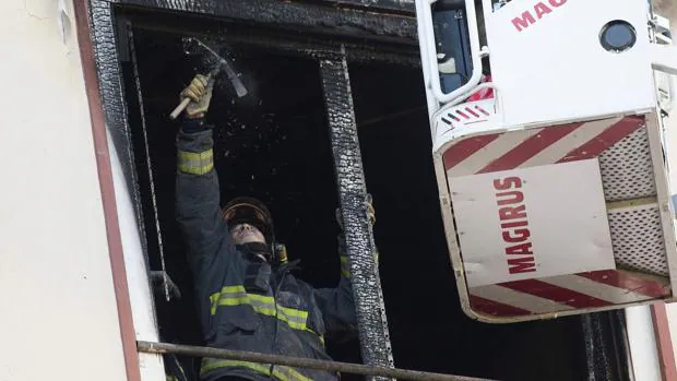 Un bombero retira restos con riesgo de desprendimiento en la ventana de la vivienda incendiada